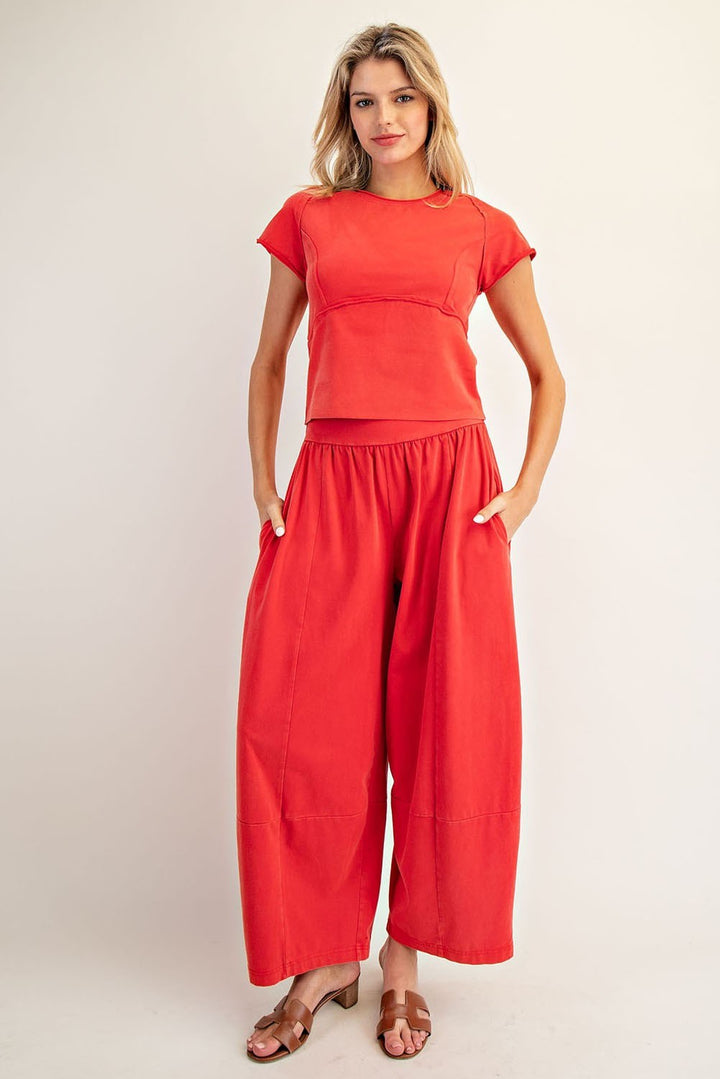 Woman wearing a red outfit with a top and wide-leg pants on a plain background