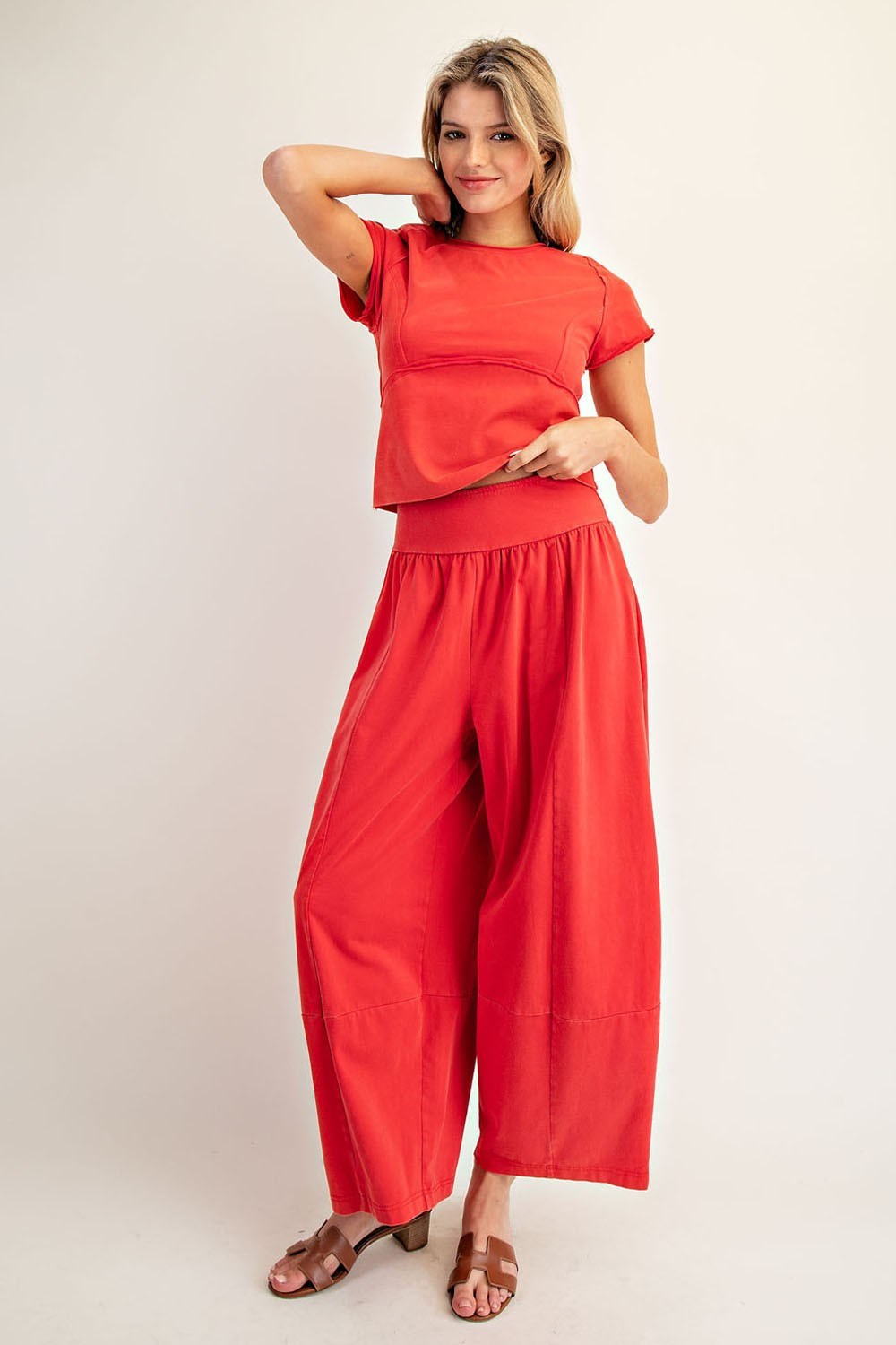 Woman wearing a red outfit with wide-leg pants on a plain background