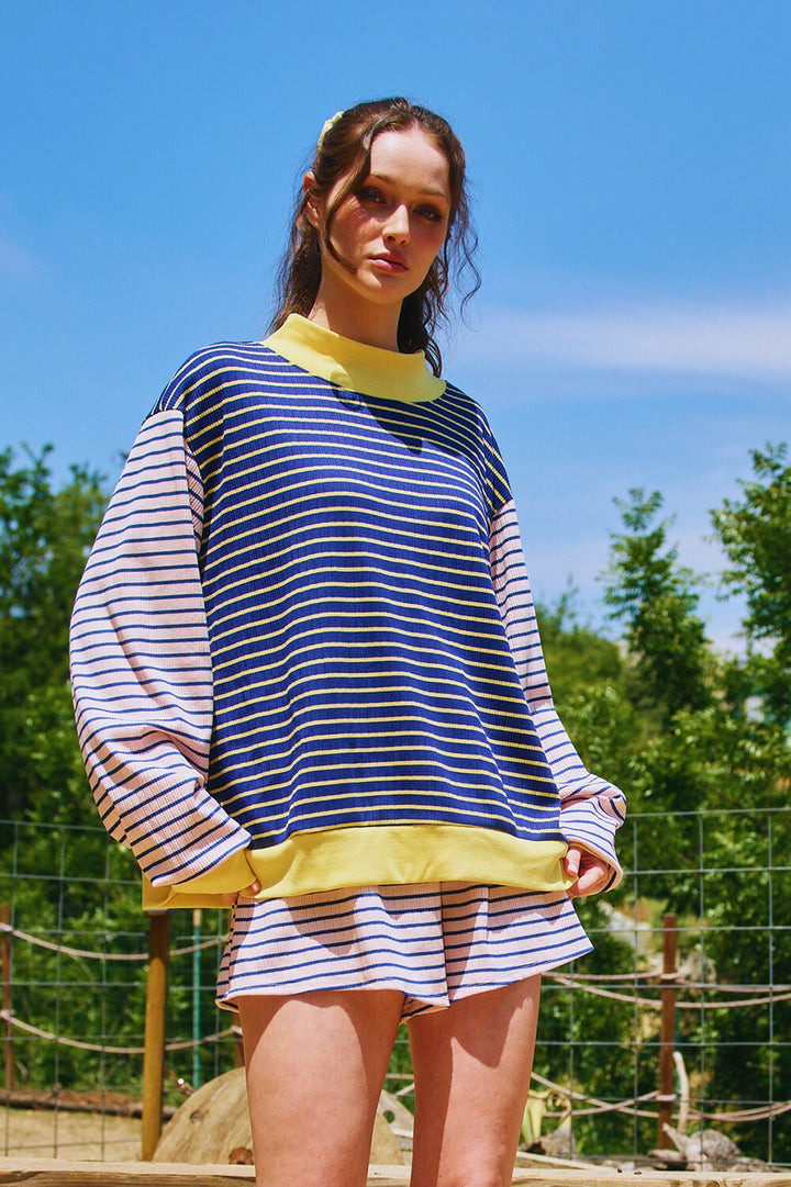 Woman wearing matching pink and navy stripe set with yellow trim outdoors