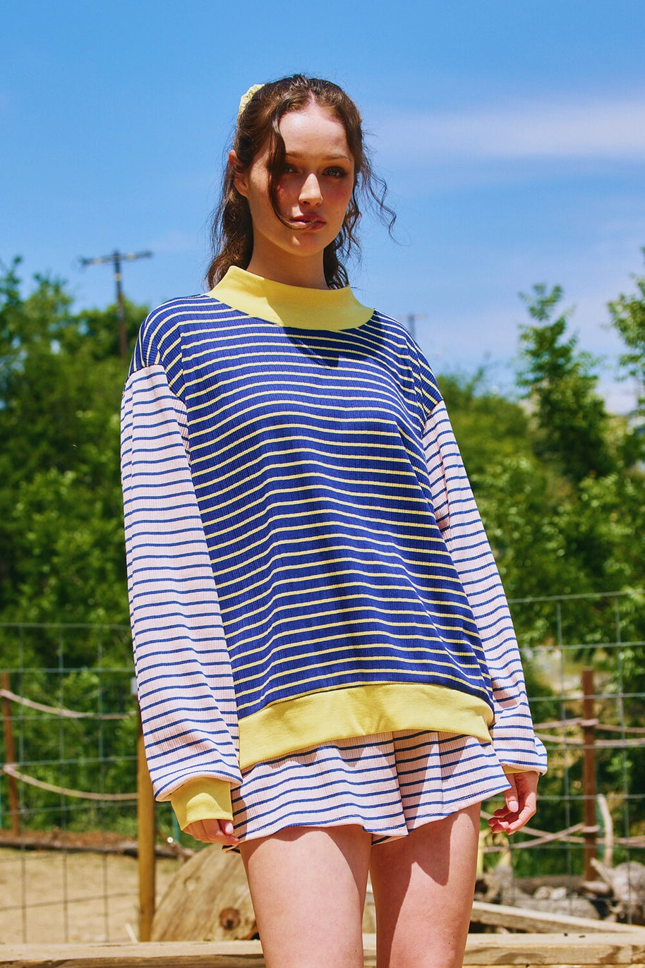 Woman wearing a blue and pink striped shirt with yellow accents outdoors