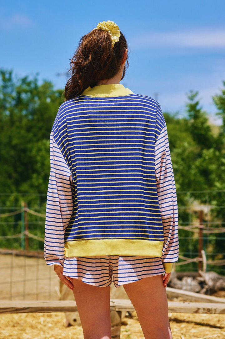 Woman wearing matching pink and navy stripe set with yellow trim outdoors