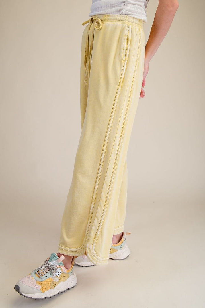 Person wearing light yellow drawstring pants on a beige background