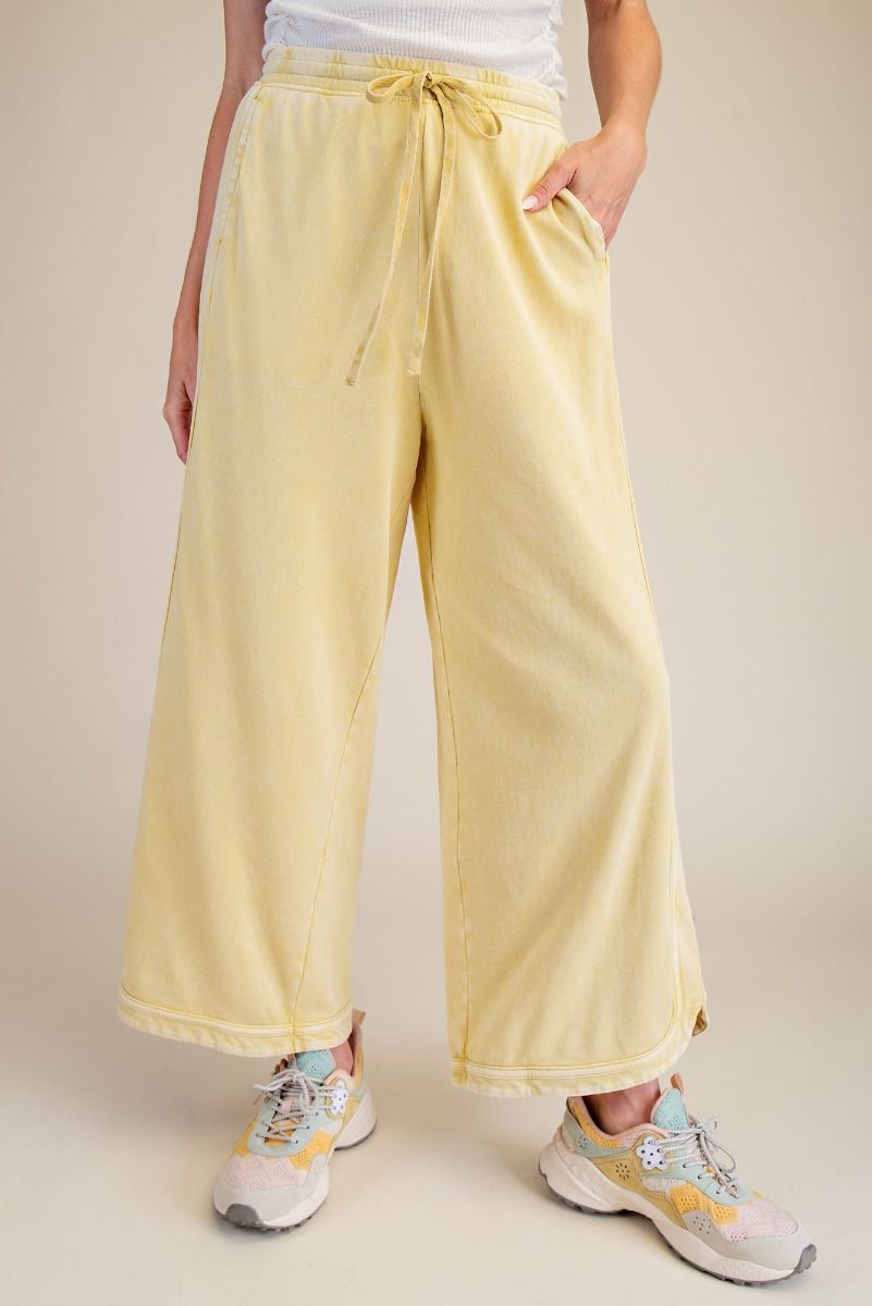Person wearing light yellow drawstring pants on a beige background