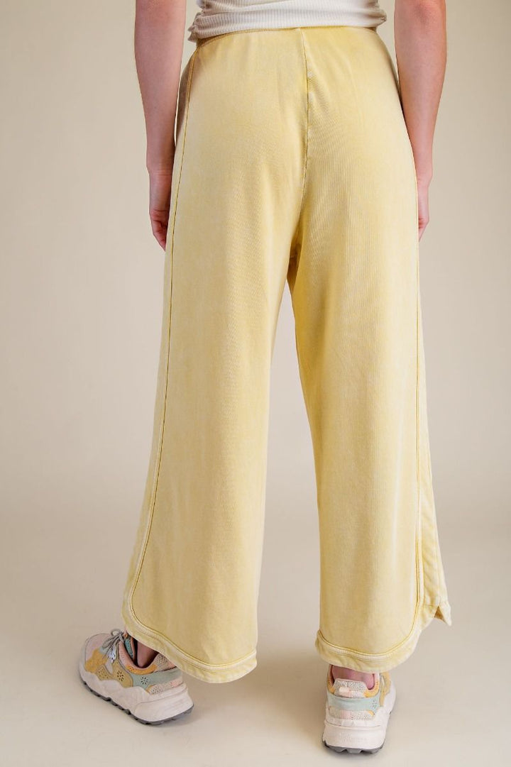 Person wearing light yellow pants with a neutral background