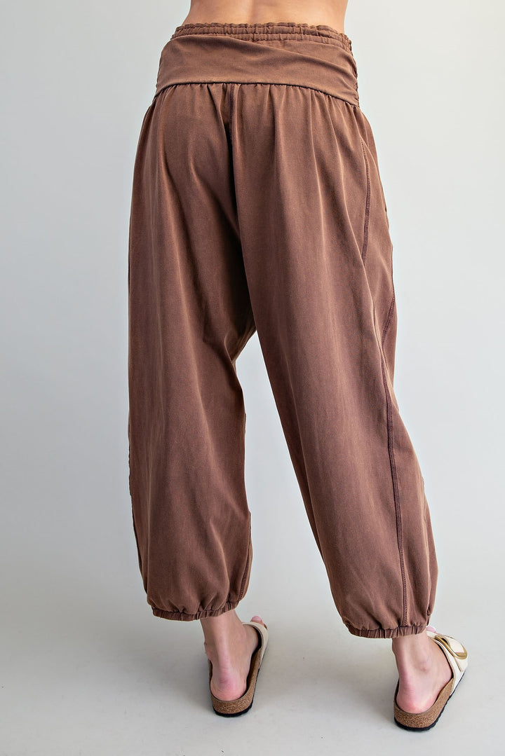 Rust brown harem-style pants with an elastic waistband and gathered ankle cuffs, shown on a model from the back against a light gray studio background.