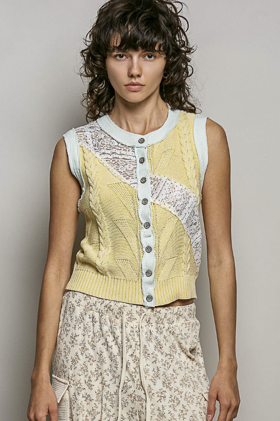 Woman wearing a yellow and white patterned sleeveless top with a plain background