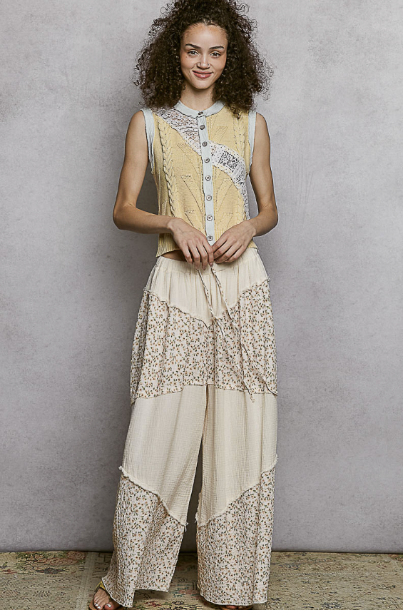 Woman wearing a sleeveless top and wide-leg pants with floral patterns against a plain background