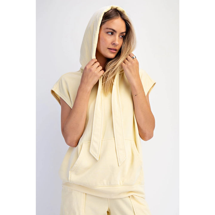 Woman wearing a light yellow outfit with a hood against a white background