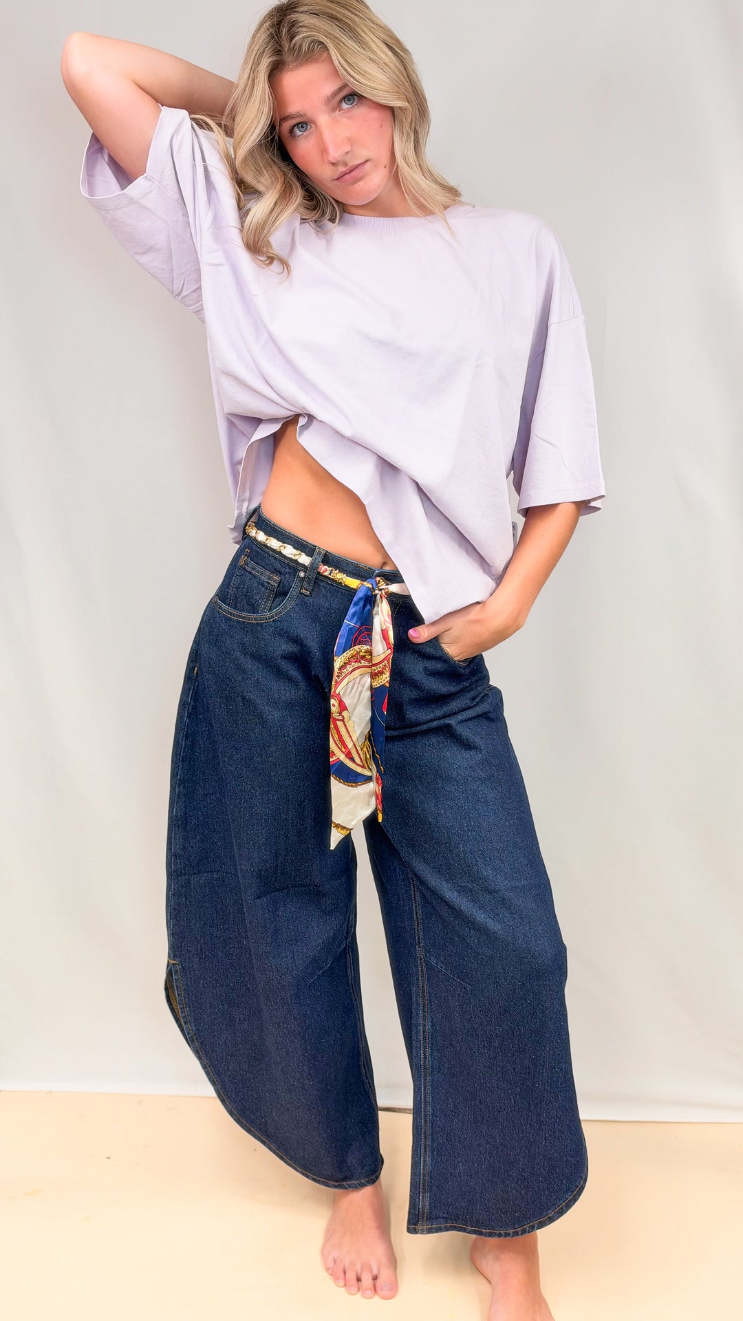 Woman wearing dark tulip hem pants with purple tee on plain background