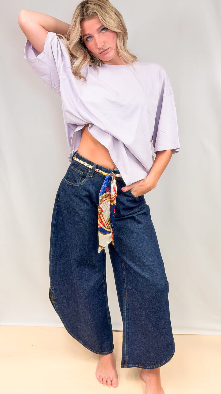 Woman wearing dark tulip hem pants with purple tee on plain background