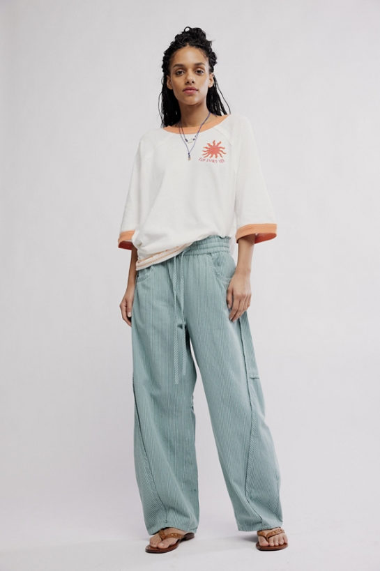 Woman wearing a white t-shirt with a red logo and light blue pants on a white background