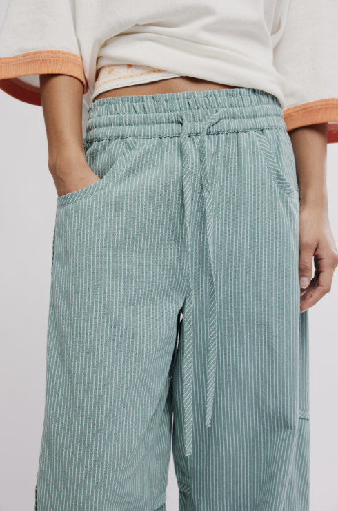 Green striped pants worn by a person on a white background