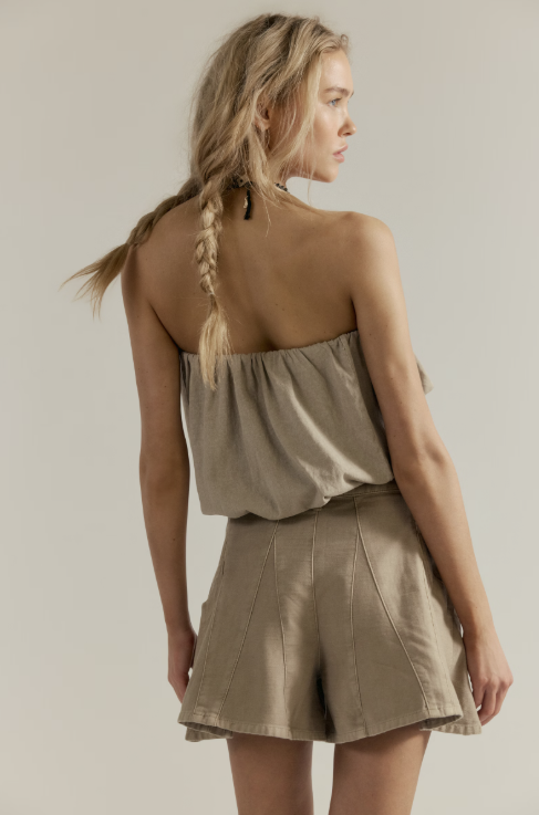 Woman wearing a beige sleeveless top and shorts set on a plain background