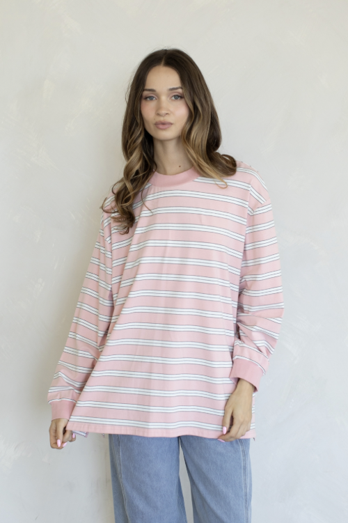 Woman wearing pink and white stripe top and jeans on plain background