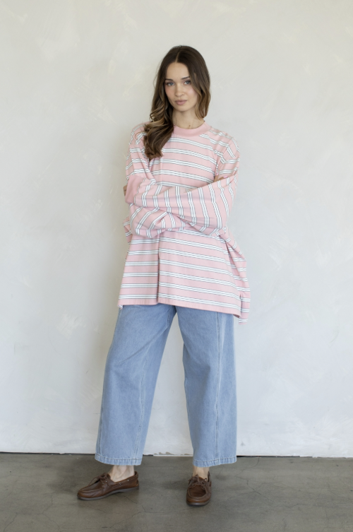 Woman wearing pink and white stripe top and jeans on plain background