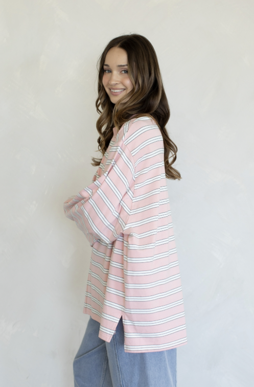 Woman wearing pink and white stripe top and jeans on plain background