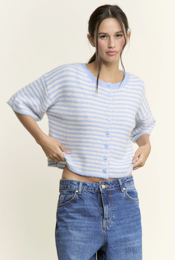 Woman wearing a blue and white striped shirt and blue jeans on a plain background