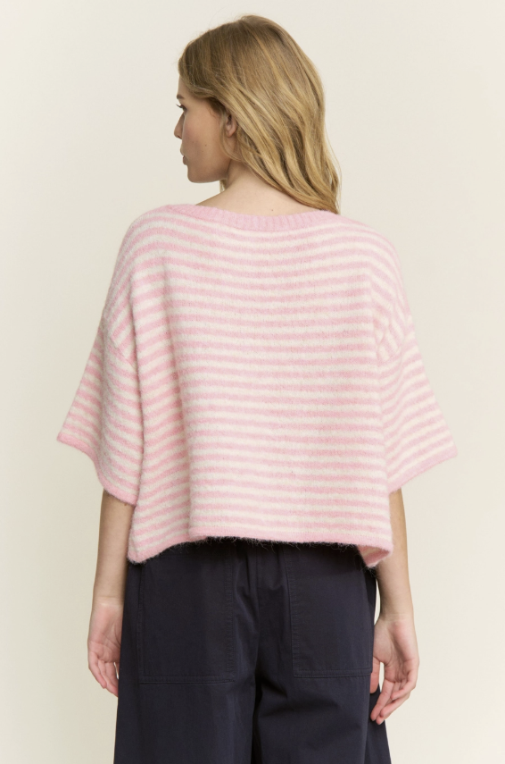 Woman wearing a pink striped sweater against a plain background