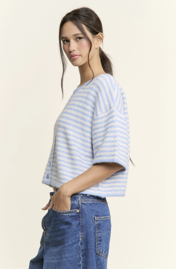 Woman wearing a striped shirt and jeans on a plain background