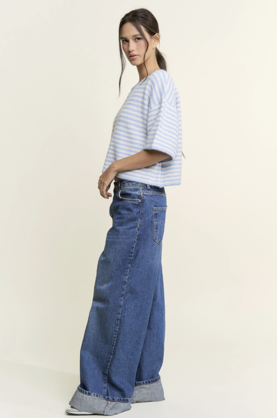 Woman wearing a striped shirt and wide-leg jeans on a plain background