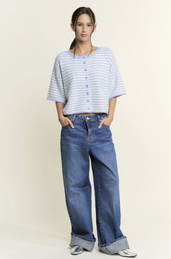 Woman wearing a striped shirt and blue jeans on a plain background