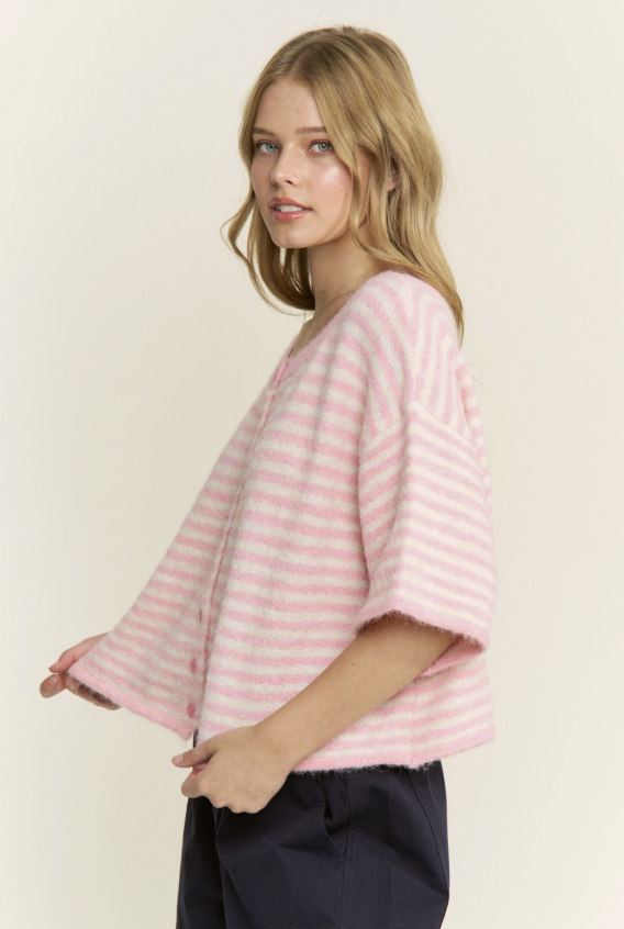 Woman wearing a pink striped sweater against a plain background