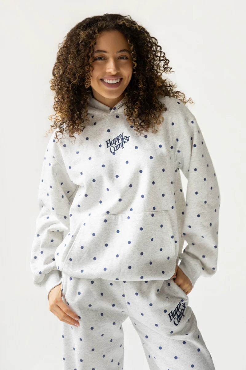 Person wearing a white hoodie and pants with polka dot pattern on a plain background