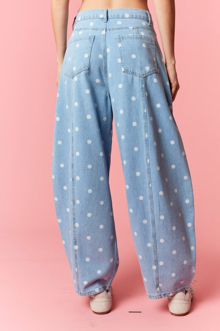 Light blue jeans with white polka dots worn by a person on a pink background