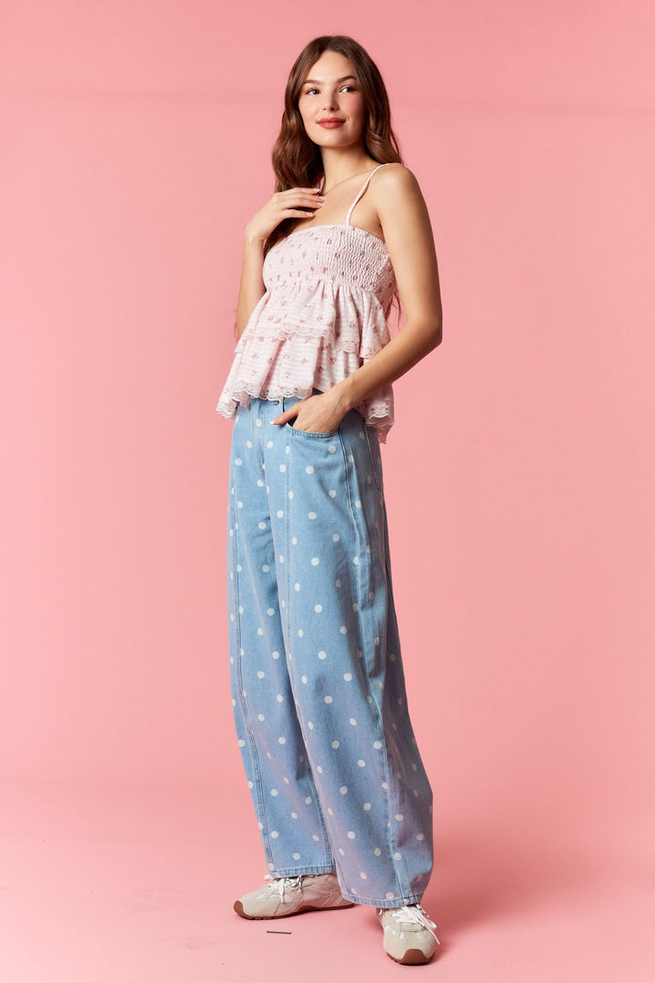 Woman wearing a pink top and blue polka dot pants on a pink background