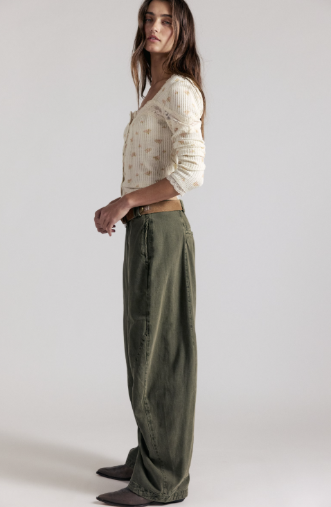 Woman wearing green pants and white shirt on grey background