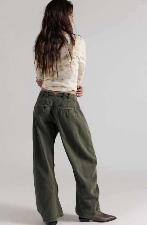 Woman wearing green pants and white top on grey background
