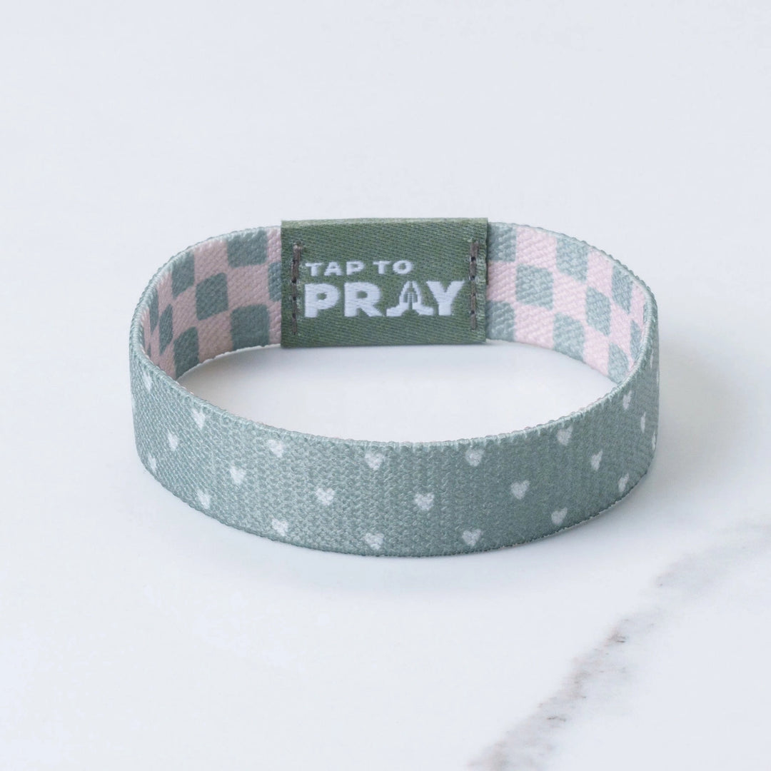 Wristband with checkered top section and polka dot bottom section on a light background