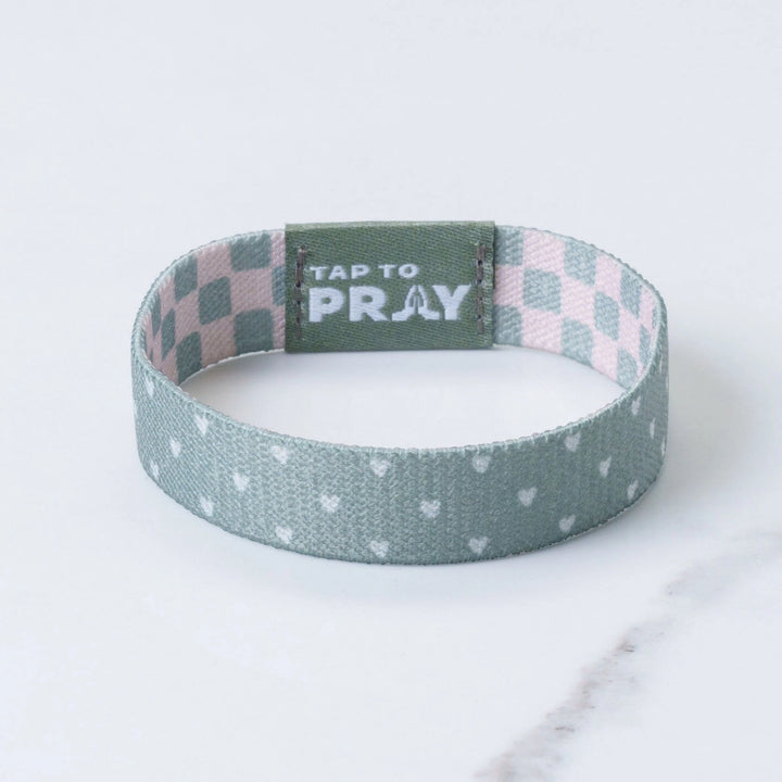 Wristband with checkered top section and polka dot bottom section on a light background