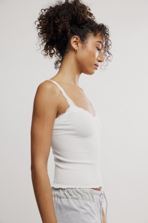 Woman wearing a white tank top against a plain background