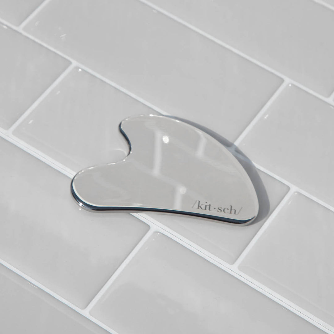 Stainless Steel Gua Sha on tile background