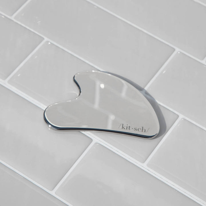 Stainless Steel Gua Sha on tile background