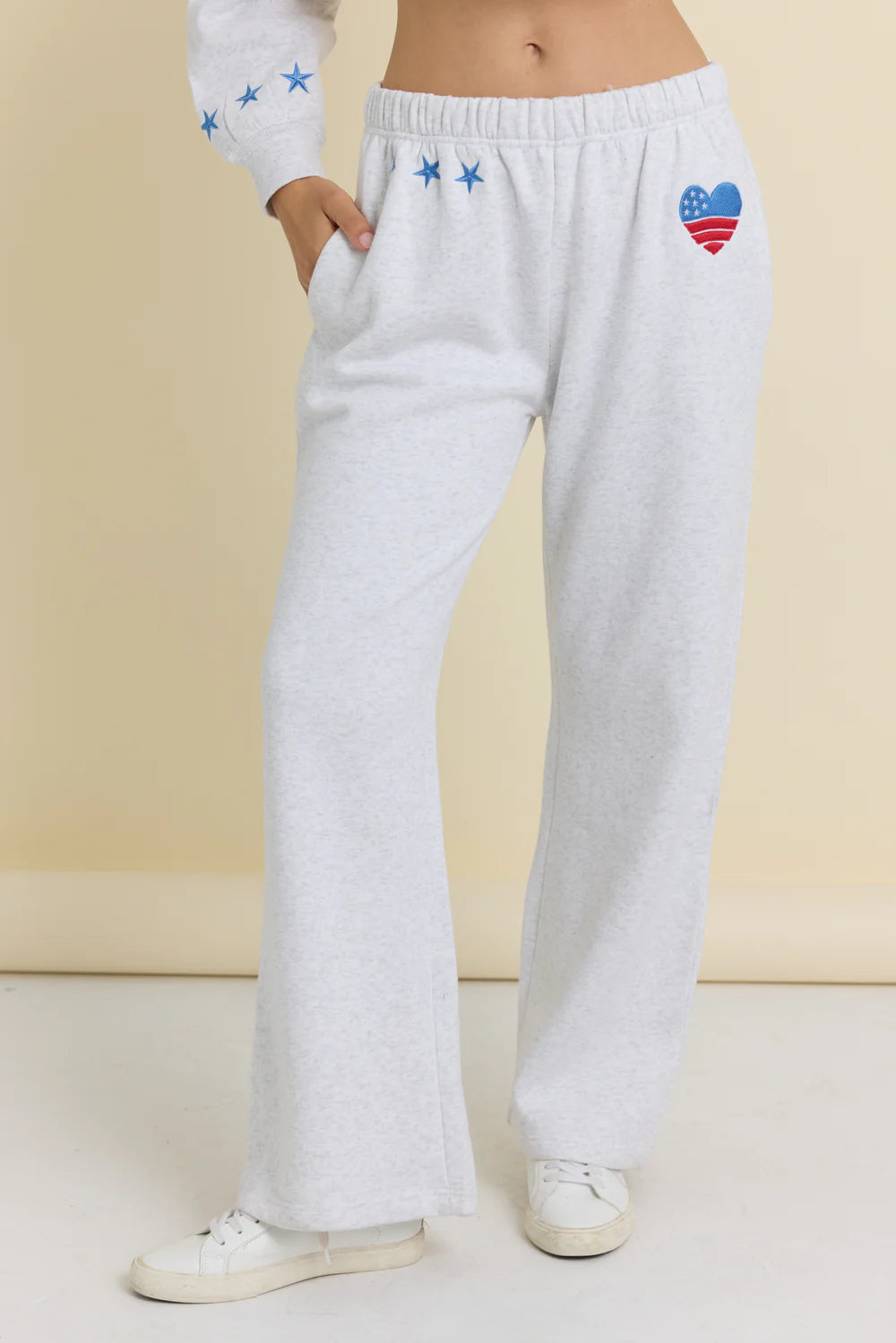 White sweatpants with colorful heart design on a beige background