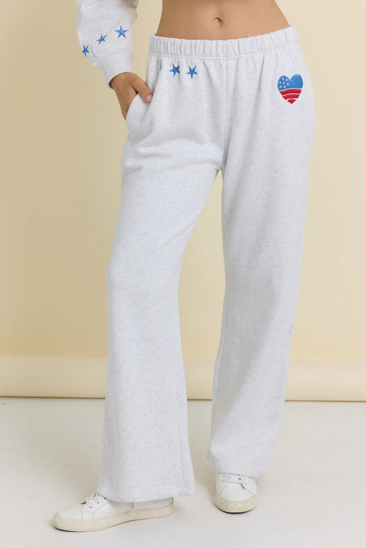 White sweatpants with colorful heart design on a beige background