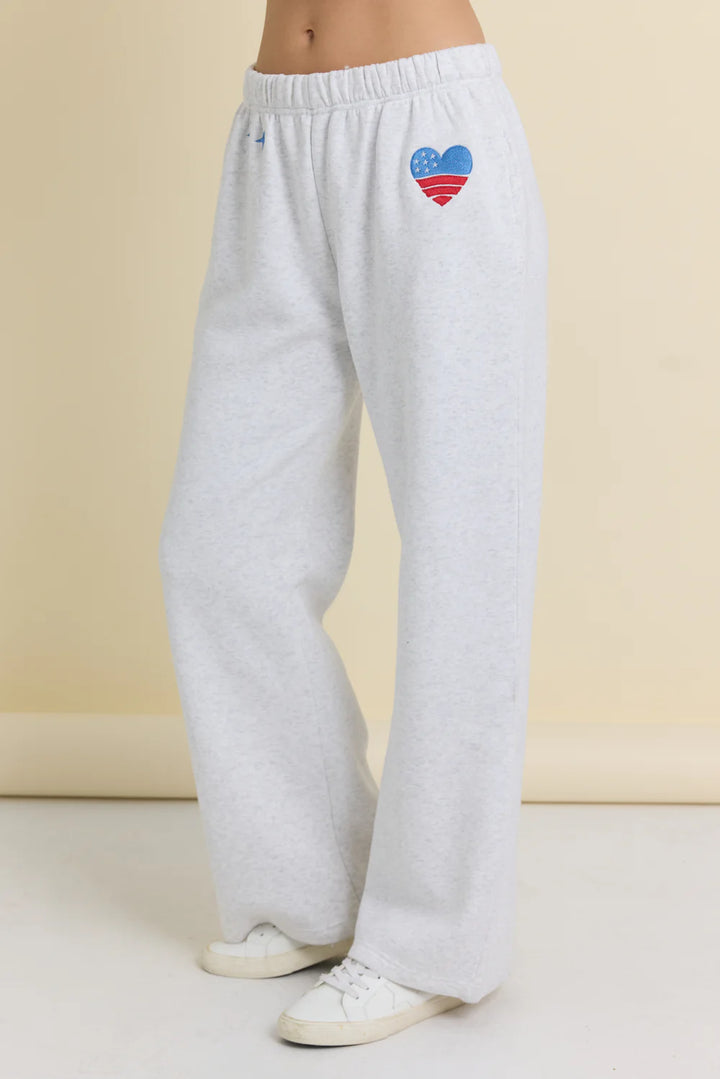 White sweatpants with a colorful heart design on a beige background