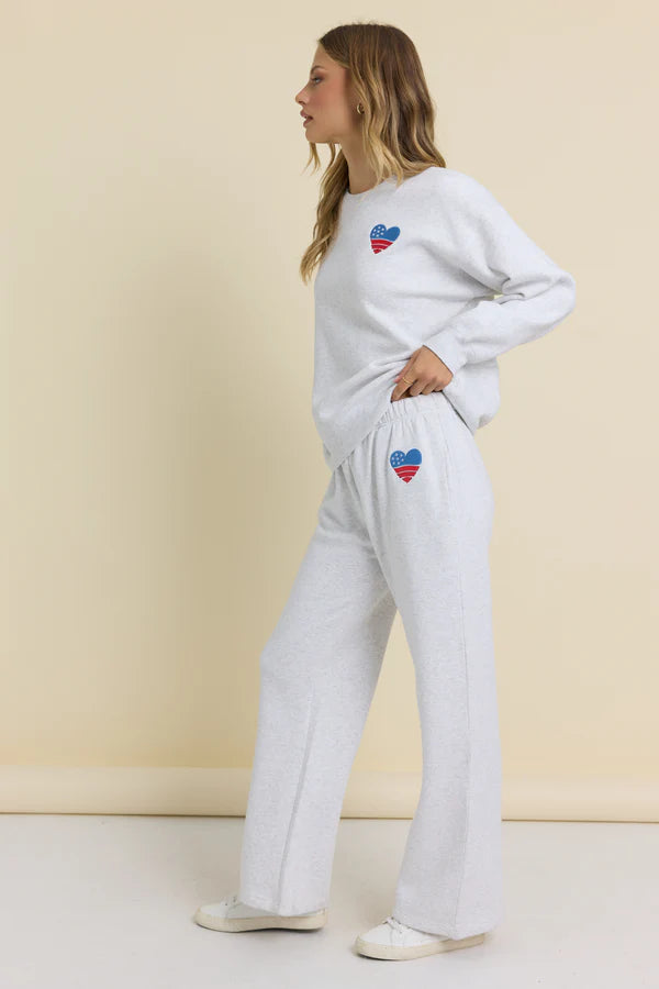 Woman wearing a light gray sweatshirt and pants with heart designs on a beige background
