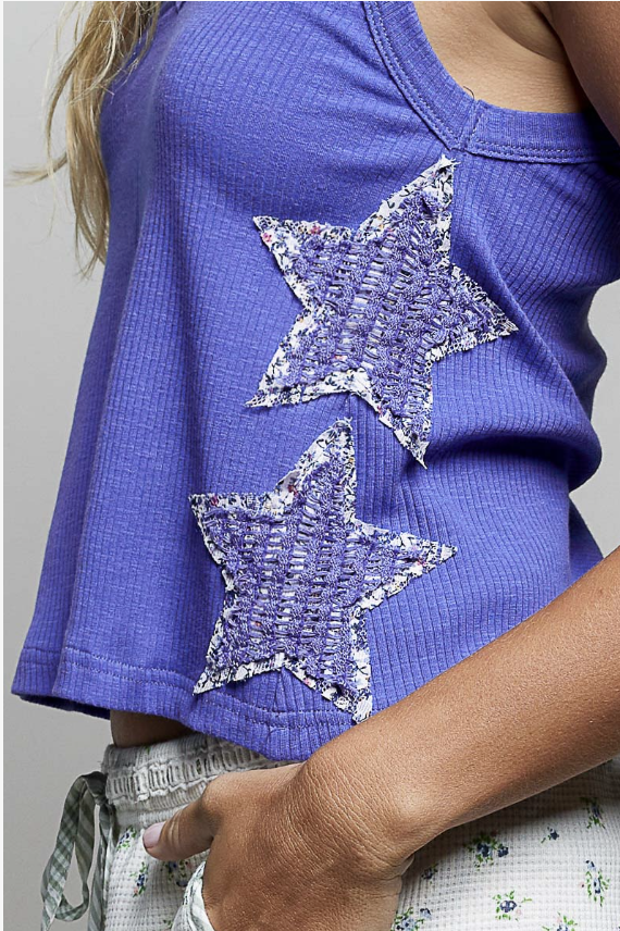 Woman wearing blue tank with patchwork stars on plain background