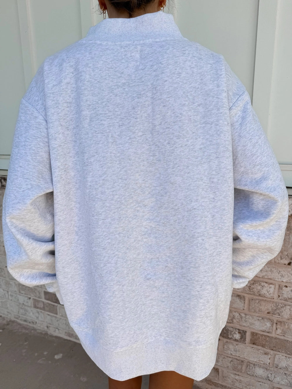 Person wearing a light blue sweater with a neutral background