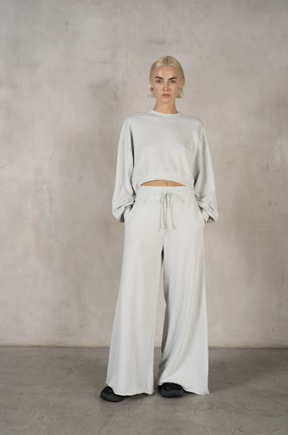 Person wearing a light gray outfit against a plain background