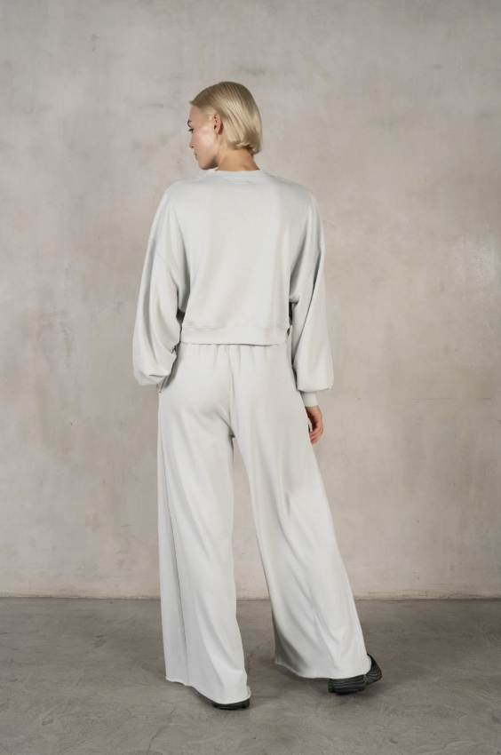 Person wearing a light gray outfit against a plain background