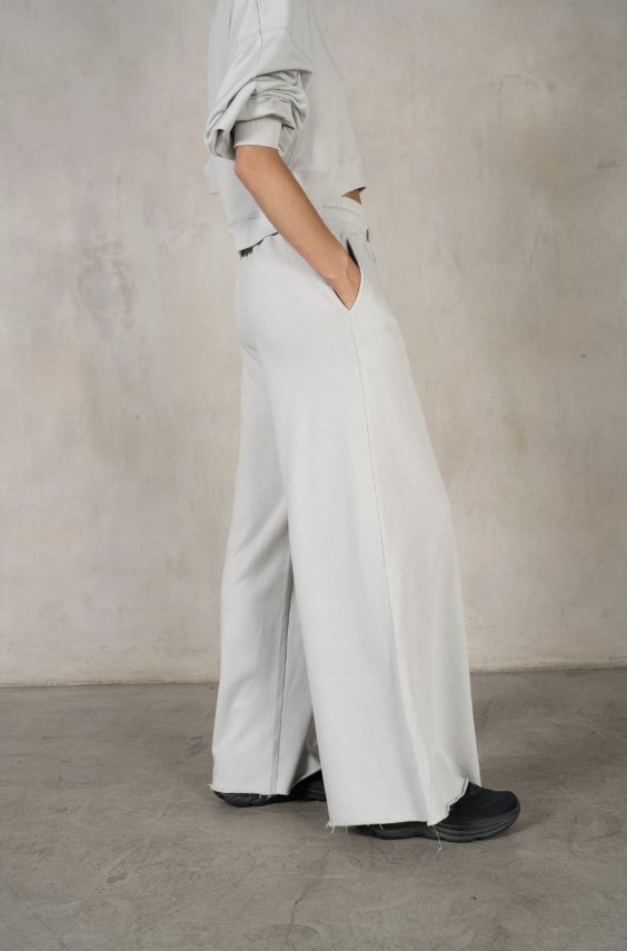 Person wearing light gray wide-leg pants and a matching top against a neutral background