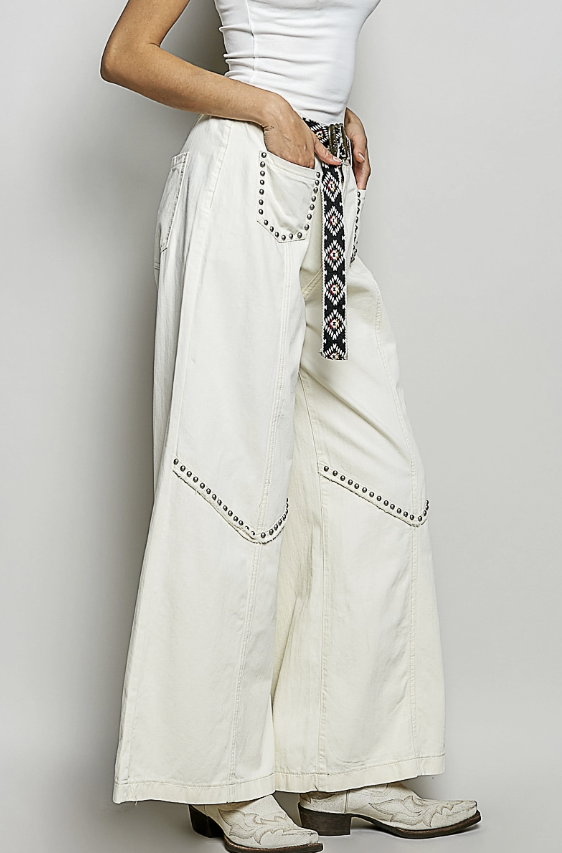 Person wearing white pants with decorative elements on a plain background