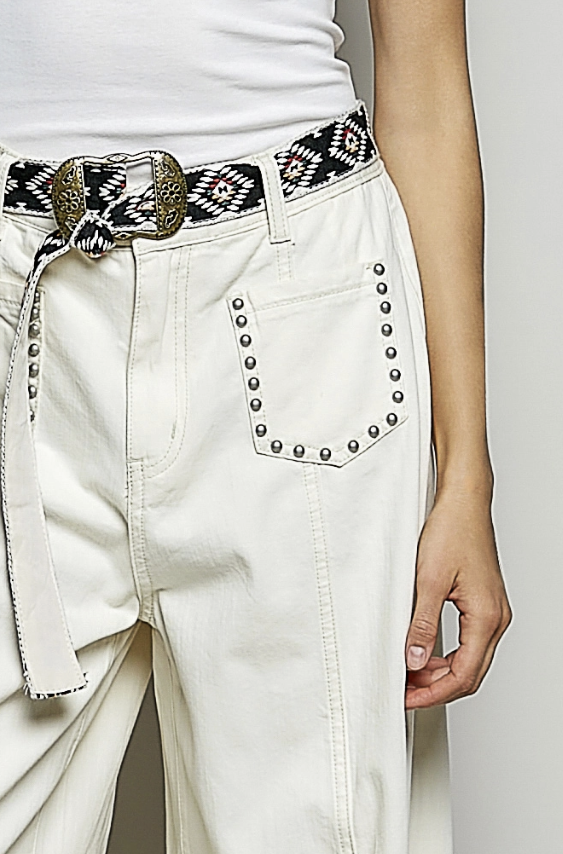 White pants with decorative belt and studded details on a plain background