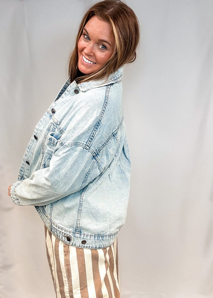 Woman wearing beige and white stripe pants and jean jacket on white background