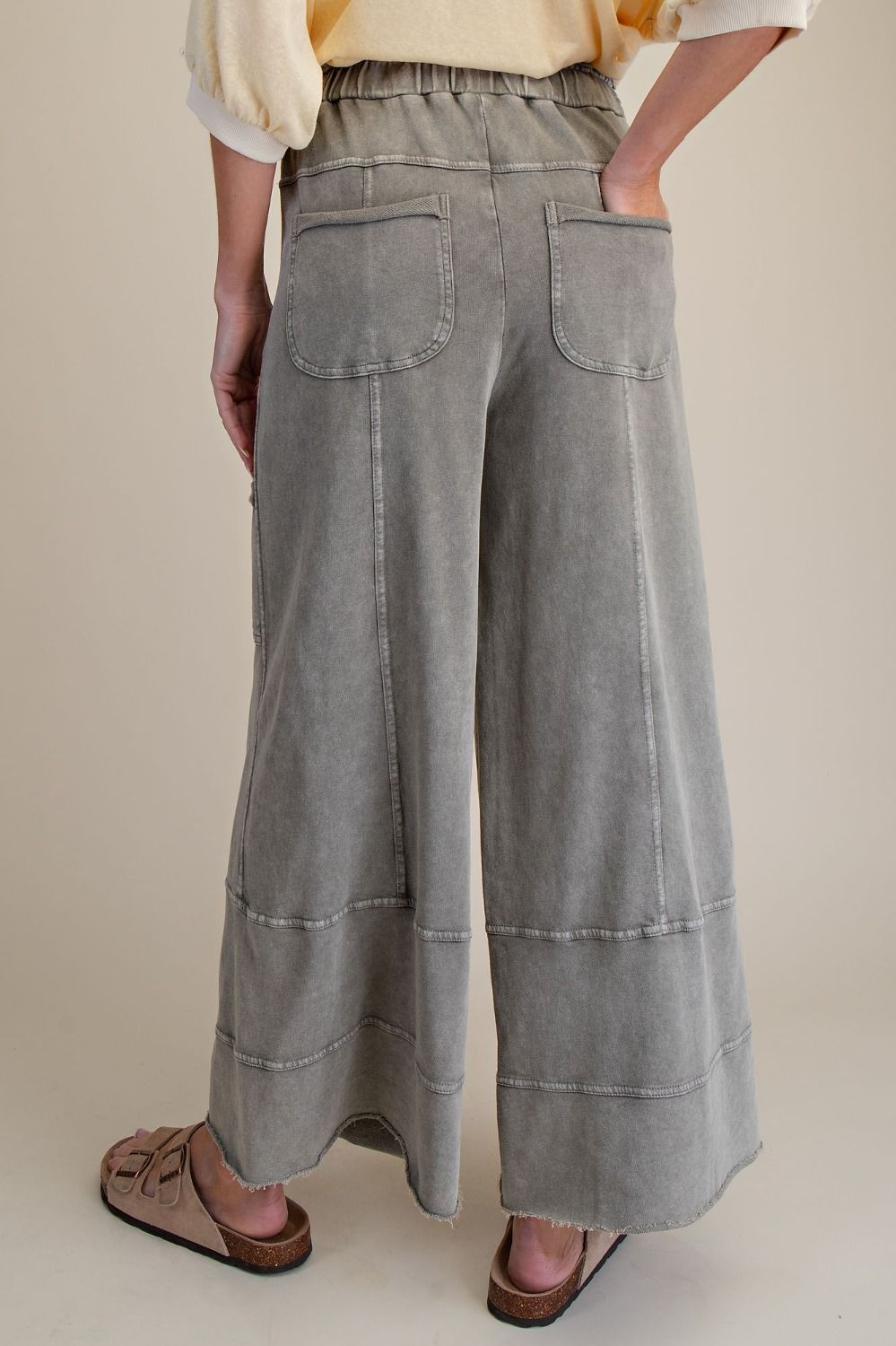 Person wearing wide-leg gray pants on a beige background