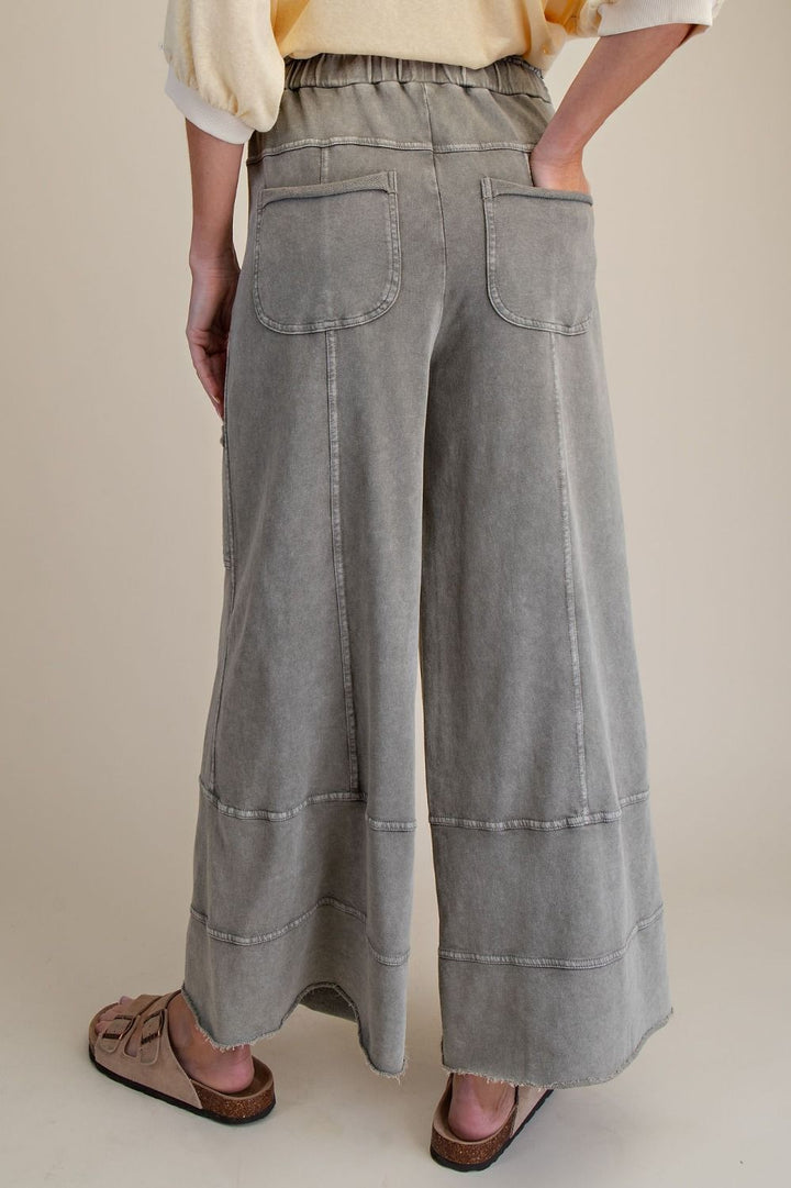 Person wearing wide-leg gray pants on a beige background